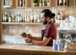 happy man or waiter with chalkboard banner at bar