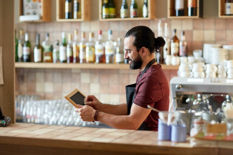 happy man or waiter with chalkboard banner at bar
